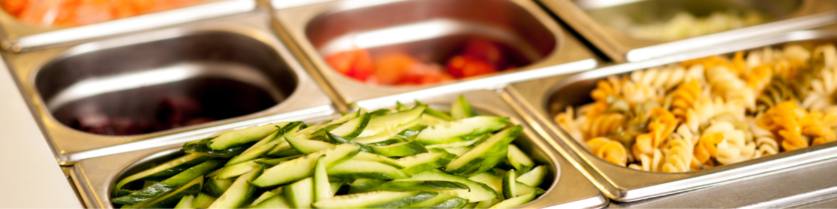 Prepared vegetables and pasta salad in stainless steel containers for a salad bar